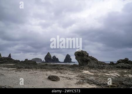 Moody Skies couvre un paysage marin féroce avec de grandes formations rocheuses et des vagues turbulentes qui s'écrasent contre eux Banque D'Images