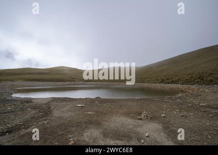 Un lac Jiaming serein niché dans les montagnes, entouré de brume en hiver Banque D'Images