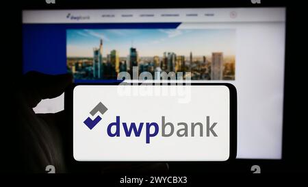 Personne tenant le téléphone portable avec le logo de la société Deutsche WertpapierService Bank AG (dwpbank) en face de la page Web de l'entreprise. Concentrez-vous sur l'affichage du téléphone. Banque D'Images