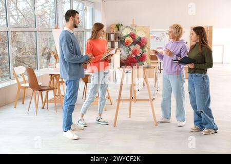 Professeur d'art mûr avec peinture donnant des leçons aux élèves à l'école Banque D'Images