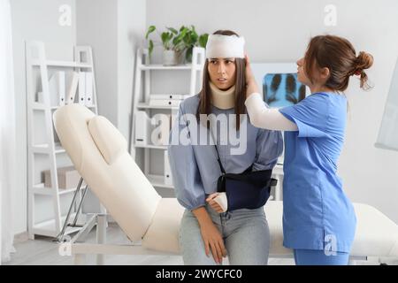 Médecin pansant la tête d'un patient après accident en clinique Banque D'Images