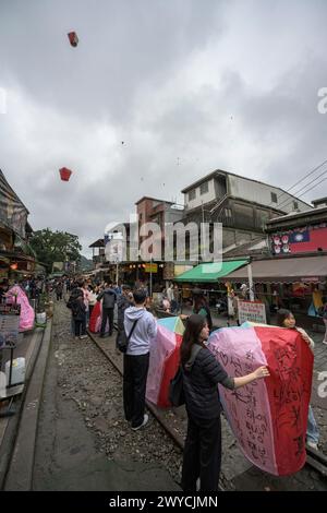 Touristes et spectateurs participent à la libération de lanternes pour faire des vœux pour la nouvelle année sur les voies ferrées à Shifen Banque D'Images