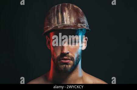 Homme bâtisseur. Gros plan portrait d'architecte masculin sérieux, entrepreneur ou ingénieur dans le casque de sécurité. Beau travailleur de la construction dans la construction de casque de sécurité Banque D'Images