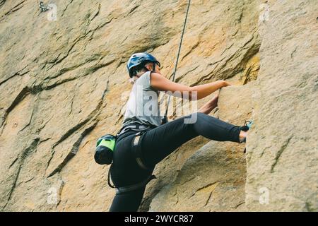 Jeune femme athlétique dans l'équipement faisant de l'escalade en plein air. Espace d'entraînement pour les activités de plein air. Sport extrême. Banque D'Images