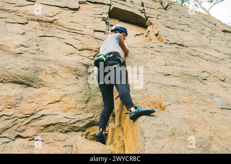 Jeune femme athlétique dans l'équipement faisant de l'escalade en plein air. Espace d'entraînement pour les activités de plein air. Sport extrême. Banque D'Images