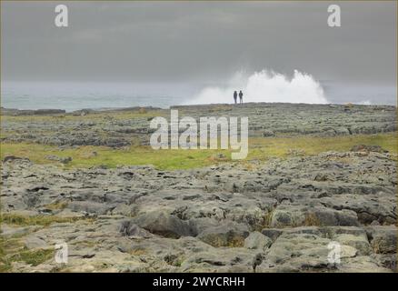 Regardant à travers un trottoir calcaire à deux personnes stoodon le bord d'un rivage comme une vague éclaboussure Banque D'Images