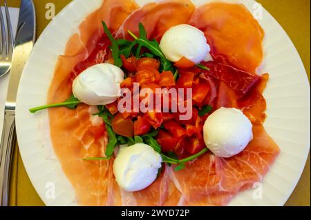 Cuisine de la région Emilie-Romagne, salade Caprese avec Prosciutto crudo, prosciutto di Parma, mozzarella et tomates, déjeuner à Parme, Italie Banque D'Images