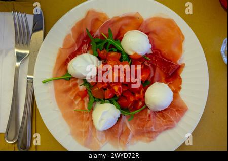 Cuisine de la région Emilie-Romagne, salade Caprese avec Prosciutto crudo, prosciutto di Parma, mozzarella et tomates, déjeuner à Parme, Italie Banque D'Images