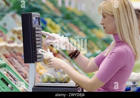 Femme pesant des fruits au supermarché. Banque D'Images