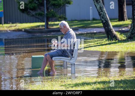 Samedi 6 avril 2024. Sydney a été frappée par un déluge de pluie au cours des dernières 48 heures, avec certaines zones, y compris Penrith recevant les précipitations les plus abondantes jamais enregistrées, à Narrabeen les résidents autour du lagon de Narabeen, sur la photo, ont été invités à évacuer en raison de la montée des niveaux d'eau du lac Narrabeen sur les plages du nord de Sydney. où plus de 150 mm de pluie sont tombés. Il y a eu plus de 50 observateurs d'inondations le long des rivières en Nouvelle-Galles du Sud et le barrage de Warragamba devrait se déverser. Homme âgé sur la photo est assis o na banc de parc dans les eaux de crue à côté du lac. Créditez Martin Berry @alamy Live news. Banque D'Images