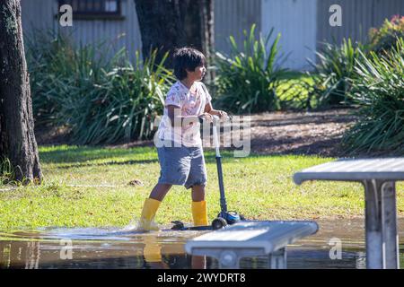 Samedi 6 avril 2024. Sydney a été frappée par un déluge de pluie au cours des dernières 48 heures, avec certaines zones, y compris Penrith recevant les précipitations les plus abondantes jamais enregistrées, à Narrabeen les résidents autour du lagon de Narabeen, sur la photo, ont été invités à évacuer en raison de la montée des niveaux d'eau du lac Narrabeen sur les plages du nord de Sydney. où plus de 150 mm de pluie sont tombés. Il y a eu plus de 50 observateurs d'inondations le long des rivières en Nouvelle-Galles du Sud et le barrage de Warragamba devrait se déverser. Jeune garçon dans des bottes jaunes joue sur son scooter dans l'eau de crue. Créditez Martin Berry @alamy Live news. Banque D'Images