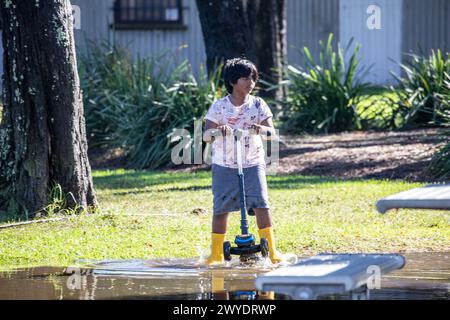 Samedi 6 avril 2024. Sydney a été frappée par un déluge de pluie au cours des dernières 48 heures, avec certaines zones, y compris Penrith recevant les précipitations les plus abondantes jamais enregistrées, à Narrabeen les résidents autour du lagon de Narabeen, sur la photo, ont été invités à évacuer en raison de la montée des niveaux d'eau du lac Narrabeen sur les plages du nord de Sydney. où plus de 150 mm de pluie sont tombés. Il y a eu plus de 50 observateurs d'inondations le long des rivières en Nouvelle-Galles du Sud et le barrage de Warragamba devrait se déverser. Jeune garçon dans des bottes jaunes joue sur son scooter dans l'eau de crue. Créditez Martin Berry @alamy Live news. Banque D'Images