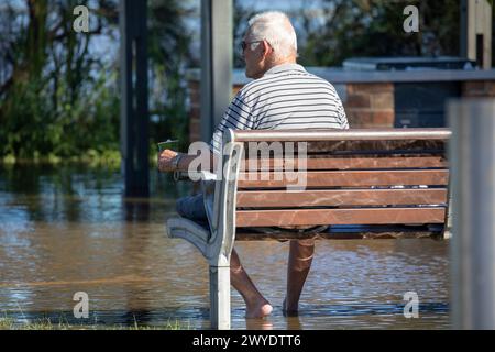 Samedi 6 avril 2024. Sydney a été frappée par un déluge de pluie au cours des dernières 48 heures, avec certaines zones, y compris Penrith recevant les précipitations les plus abondantes jamais enregistrées, à Narrabeen les résidents autour du lagon de Narabeen, sur la photo, ont été invités à évacuer en raison de la montée des niveaux d'eau du lac Narrabeen sur les plages du nord de Sydney. où plus de 150 mm de pluie sont tombés. Il y a eu plus de 50 observateurs d'inondations le long des rivières en Nouvelle-Galles du Sud et le barrage de Warragamba devrait se déverser. Homme âgé photographié assis sur un banc de parc dans les eaux de crue au bord du lac. Créditez Martin Berry @alamy Live news. Banque D'Images