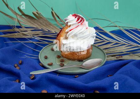 Gâteau Savarin avec glaçage rouge et crème fouettée sur tissu bleu Banque D'Images