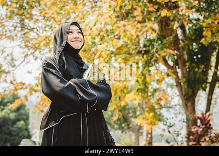 Femme musulmane niqab lisant et apprenant le Coran et la foi le livre du Saint Al Coran. Arabe saoudienne noire chador dame. Banque D'Images