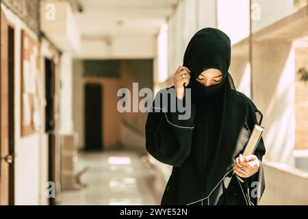 Femme musulmane niqab lisant et apprenant le Coran et la foi le livre du Saint Al Coran. Arabe saoudienne noire chador dame. Banque D'Images