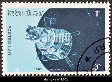 Timbre-poste annulé imprimé par le Laos, qui montre le satellite 'Spoutnik-2', vers 1987. Banque D'Images