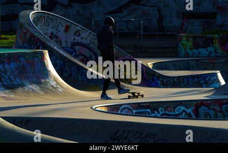 06 avril 2024, Hesse, Francfort/main : un homme pratiquant avec sa planche dans le parc du port aux premières heures de la matinée. Photo : Andreas Arnold/dpa Banque D'Images