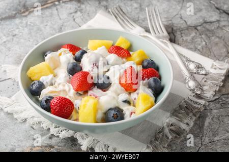 Salade de fromage à la crème avec fraises, bleuets, ananas gros plan dans un bol sur une table en marbre. Horizontal Banque D'Images