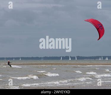 Les kitesurfs et les véliplanchistes profitent au maximum d'une journée blusteuse sur le Solent à Stokes Bay, Lee-on-Solent, Gosport Hampshire, Angleterre, Royaume-Uni Banque D'Images