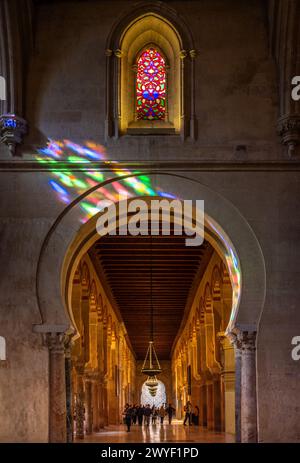 Les reflets de vitraux des fenêtres gothiques dansent sur une arche en fer à cheval islamique dans la mosquée de Cordobas. Banque D'Images