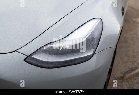 Kiev, Ukraine. 6 avril 2024. Phare. Phare LED d'une voiture électrique grise moderne Tesla close-up. Banque D'Images