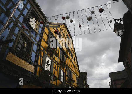 Vue panoramique des bâtiments à colombages avec des décorations de Noël festives sur la rue du général de Gaulle, la rue principale de Riquewihr en Alsace, France. Banque D'Images