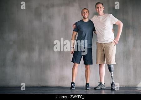 heureux, physiothérapeute et homme handicapé en portrait avec jambe prothétique dans un espace maquette. Studio, arrière-plan et soins orthopédiques ou Banque D'Images