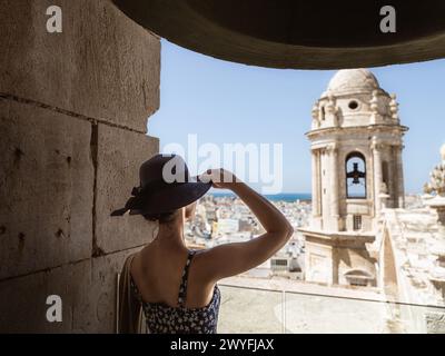 Une belle jeune femme touriste dans une robe de soleil et un chapeau regardant de la tour de la cathédrale de Cadix vers la vieille ville, vacances d'été Banque D'Images