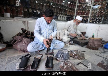 Cordonniers préparant des chaussures pour les clients à porter sur Eid- ul- Fitar dans sa boutique avant Eid-ul-Fitar pendant le mois Saint de Ramadan-ul-Moubarak, au Namak Mandi Bazar à Peshawar le samedi 6 avril 2024. Banque D'Images