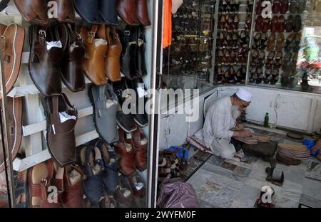 Cordonniers préparant des chaussures pour les clients à porter sur Eid- ul- Fitar dans sa boutique avant Eid-ul-Fitar pendant le mois Saint de Ramadan-ul-Moubarak, au Namak Mandi Bazar à Peshawar le samedi 6 avril 2024. Banque D'Images