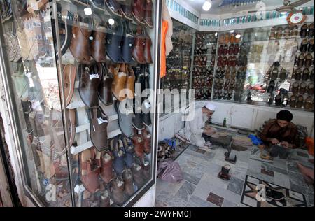 Cordonniers préparant des chaussures pour les clients à porter sur Eid- ul- Fitar dans sa boutique avant Eid-ul-Fitar pendant le mois Saint de Ramadan-ul-Moubarak, au Namak Mandi Bazar à Peshawar le samedi 6 avril 2024. Banque D'Images