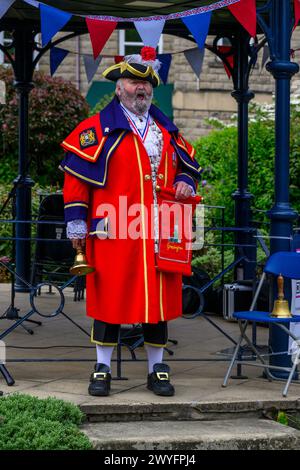 Crier de la ville masculine (livrée de crieur tressé rouge coloré) proclamant une annonce et faisant une proclamation publique bruyante - Ilkley, West Yorkshire Angleterre Royaume-Uni. Banque D'Images