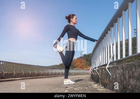 coureuse féminine faisant des exercices d'étirement des jambes d'échauffement à l'extérieur Banque D'Images