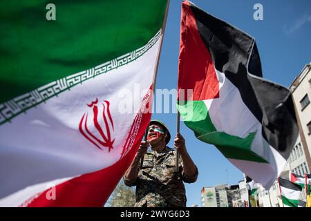 Téhéran, Iran. 05th Apr, 2024. Avec son visage peint aux couleurs du drapeau iranien, un homme chante des slogans alors qu'il agite les drapeaux iranien et palestinien dans le rassemblement annuel pour marquer la Journée de Qods, ou Journée de Jérusalem, en soutien aux Palestiniens, à Téhéran, Iran, vendredi 5 avril, 2024. lors du rassemblement à Téhéran, des milliers de personnes ont assisté à un cortège funèbre pour les sept membres des Gardiens de la révolution tués dans une frappe aérienne largement attribuée à Israël qui a détruit lundi le consulat iranien dans la capitale syrienne. (Photo de Sobhan Farajvan/Pacific Press/Sipa USA) crédit : Sipa USA/Alamy Live News Banque D'Images