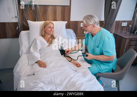 Clinicien effectuant l'examen physique du patient à l'aide d'un sphygmomanomètre Banque D'Images