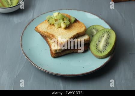 Griller le pain sur une assiette avec des tranches de kiwi sur une assiette. Petit déjeuner sain. Banque D'Images