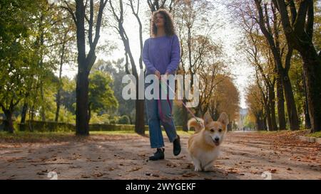 Caucasien jeune femme fille propriétaire d'animal domestique femme foulée avec chien chiot en laisse marchant dans la ville heureux petit chien mignon gallois corgi courir rue dans Banque D'Images