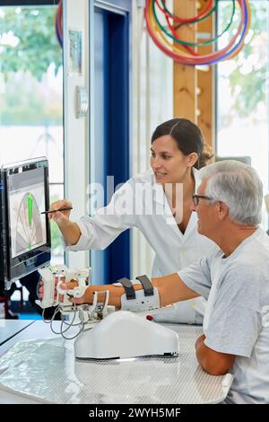 Thérapeute et patient avec robot d’assistance pour la rééducation des membres supérieurs, le robot ArmAssist permet un entraînement passif, assisté et actif du bras et de la main, permettant le traitement de la plupart des patients atteints d’AVC. Dispositif médical pour traitement neurologique. La plate-forme logicielle permet une évaluation à distance des progrès du patient et une gestion de la thérapie basée sur des jeux sérieux, qui motivent les patients à participer activement à leur rééducation et à maximiser. The Outcome, unité de technologie de la santé, Tecnalia Research & innovation, Adacen, Centre de traitement et de réadaptation des lésions cérébrales, M. Banque D'Images