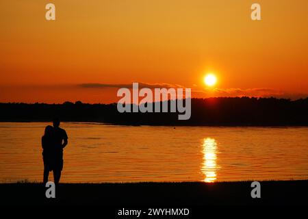 Un jeune couple adulte apprécie la vue du coucher du soleil sur le fleuve Mississippi près de Memphis, tandis que le coucher du soleil les rend en silhouette Banque D'Images