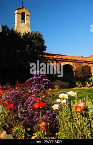 Un jardin luxuriant fleurit à la lumière du soleil à la Mission historique San Juan Capistrano en Californie Banque D'Images