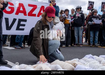 Une femme portant un keffiyeh prend un moment en déposant des effigies d’enfants palestiniens morts enveloppés dans un tissu blanc. Un petit groupe de manifestants s’est rassemblé au bout de la rue où vit le sénateur Chuck Schumer pour exiger la fin immédiate de tout financement américain en Israël. Dirigé par le groupe militant Jewish Voice for Peace, le groupe traverse un marché fermier le long de Prospect Park portant des banderoles et des effigies d'enfants palestiniens tués à Gaza par les bombardements israéliens lors de la guerre israélo-Hamas. (Photo Syndi Pilar/SOPA images/SIPA USA) Banque D'Images