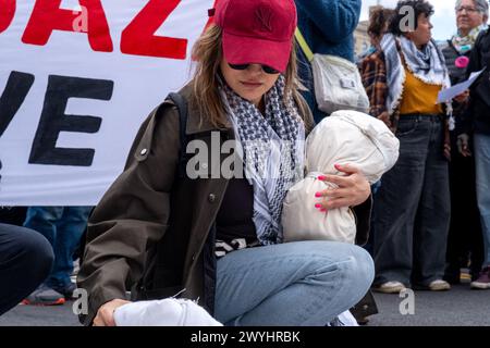 Une femme portant un keffiyeh prend un moment en déposant des effigies d’enfants palestiniens morts enveloppés dans un tissu blanc. Un petit groupe de manifestants s’est rassemblé au bout de la rue où vit le sénateur Chuck Schumer pour exiger la fin immédiate de tout financement américain en Israël. Dirigé par le groupe militant Jewish Voice for Peace, le groupe traverse un marché fermier le long de Prospect Park portant des banderoles et des effigies d'enfants palestiniens tués à Gaza par les bombardements israéliens lors de la guerre israélo-Hamas. (Photo Syndi Pilar/SOPA images/SIPA USA) Banque D'Images