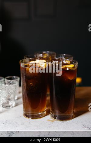 Plusieurs verres de cola glacé sur un comptoir, présentant une option de boisson rafraîchissante pour les rassemblements sociaux ou une journée chaude. Banque D'Images