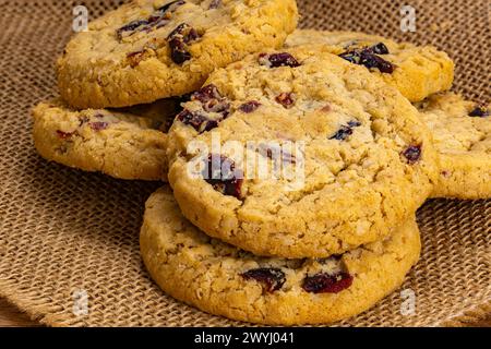 Pile de flocons d'avoine faits maison circulaires et biscuits aux canneberges sur la toile du sac. Banque D'Images