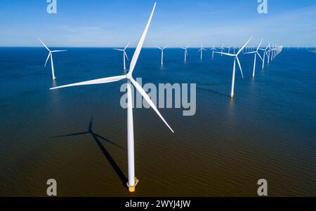 Un groupe d'élégants moulins à vent planent gracieusement au-dessus de la surface calme et réfléchissante de l'eau à Flevoland pendant la saison vibrante du printemps. drone vue aérienne des éoliennes énergie verte Banque D'Images