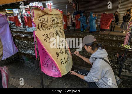 Jeune homme peint soigneusement la calligraphie sur une grande lanterne céleste pour faire un vœu pour le nouvel an chinois Banque D'Images