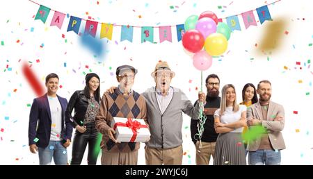 Amis seniors avec un cadeau et des ballons célébrant l'anniversaire avec un groupe de jeunes isolés sur fond blanc Banque D'Images