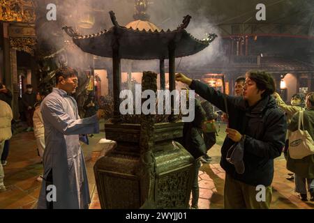 Des dévots priant dans le temple de Baoan rempli de fumée d'encens, lors d'une cérémonie du nouvel an chinois Banque D'Images
