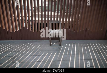 La vieille chaise en bois est en face du mur, que la lumière du soleil traverse. Coin détente dans la journée ensoleillée avec une bonne ambiance, espace pour le texte, Banque D'Images